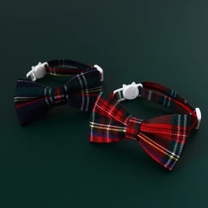 Detail view of plaid pet collars with cat-shaped safety buckles on green background