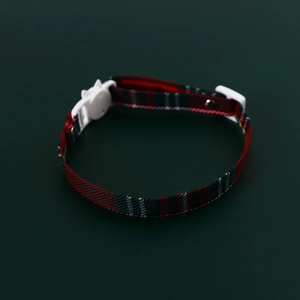 Detailed view of red and green plaid pet collar with a white cat-shaped plastic buckle
