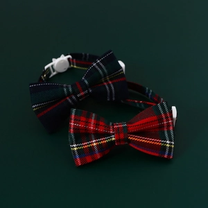 Detail of adjustable plaid pet collars with bows and buckles on dark green surface