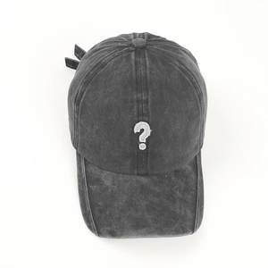 Dettaglio del ricamo punto interrogativo bianco su cappellino in denim lavato vintage