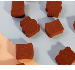 Close-up of bear-shaped and toast-shaped brown makeup sponges with smiley faces