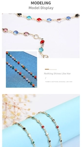 Detail of golden metal eyewear chain featuring multi-colored crystals and star shaped charms