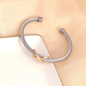 Elegant stainless steel cable twist bangle with a gold infinity knot in a minimalist style