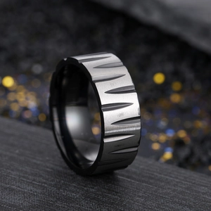 Macro detail of black brushed stainless steel ring with triangular geometric engravings