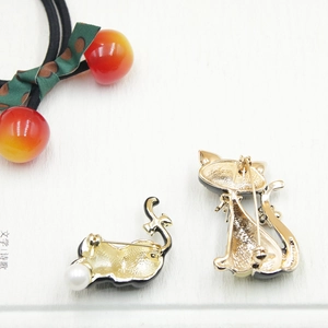 Detailed back view of gold cat brooches with pin closure and faux pearl accent