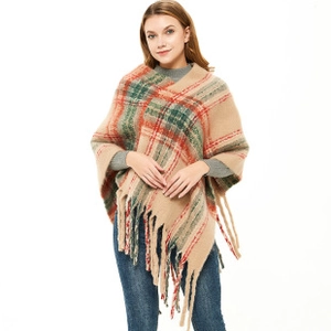 Detail of soft thick plaid knit poncho with fringe tassels and colorful grid pattern