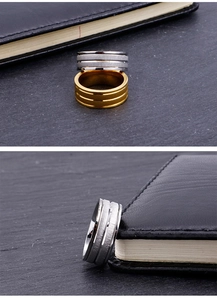 Detail view of brushed titanium steel rings in gold and silver on stone surface