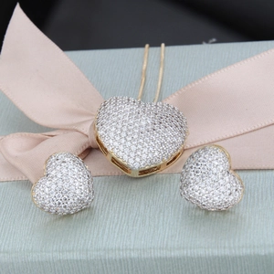 Close-up of heart-shaped necklace and stud earrings set with sparkling zircon pavé