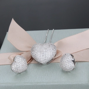 Macro shot of colorful cubic zirconia heart necklace and stud earrings set on a silk gift box