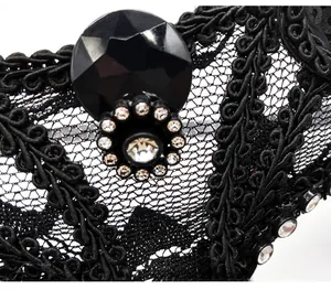 Detailed macro shot of black lace fox mask with intricate embroidery and black gemstone
