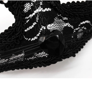 Detailed macro shot of black lace fox mask featuring a faceted heart gemstone center