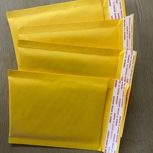 Bulk yellow bubble padded mailers with self-adhesive seal strips on wooden background