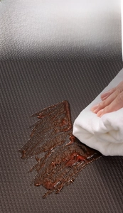 Detail showing deep brown woven PU leather mat with waterproof and oil-resistant coating
