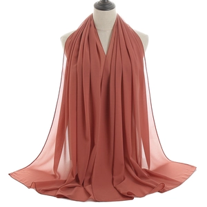 Detail of rust red chiffon hijab showing lightweight breathable fabric texture on a mannequin
