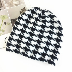 Detail of knit beanie featuring black and white houndstooth pattern on soft fabric