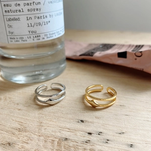 Close-up of minimalist double-layer wave open rings in silver and gold on wood