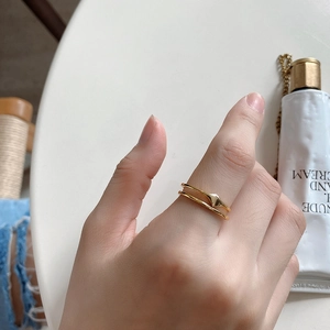 Detail of minimalist double-layered gold ring with a geometric diamond accent on hand