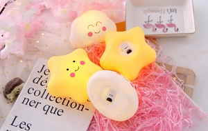 Close-up of glowing star and cloud shape night lights with warm light and smiley faces