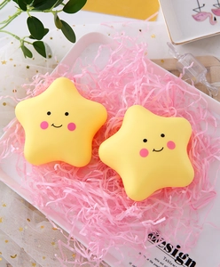 Close-up of two smiling yellow star night lights in a gift box with pink raffia