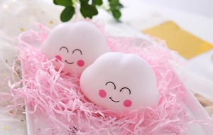 Close-up of cute smiling cloud night lights in a gift tray with pink paper shreds