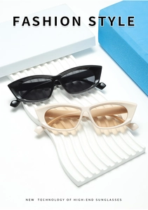 Detail view of retro cat eye sunglasses in black and cream on wave display stand