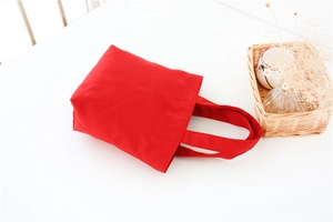 Flat lay of red canvas bento bag with minimalist handles on a clean white surface