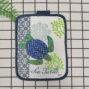 Close-up of a thick cotton sea turtle print kitchen heat insulation mat with hanging loop