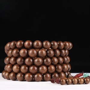 Macro detail of 12mm sandalwood beads showing golden silk grain and 130cm long craftsmanship