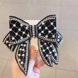 Detail of a black velvet bow hair clip with white pearls and sparkling rhinestones