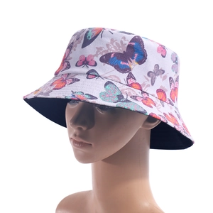 Detail of white canvas bucket hat with colorful butterfly prints and black inner brim