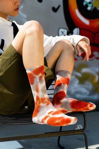 Detail of tie-dye crew socks in orange and grey mix on a street style background