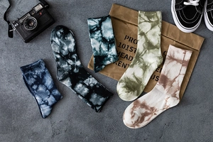 Tie-dye mid-calf crew socks displayed in various retro patterns on a grey stone texture