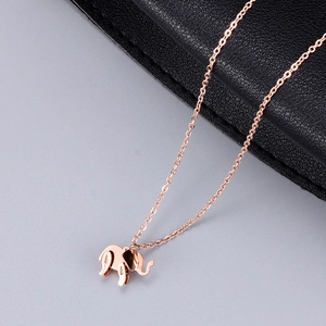 Close-up of rose gold elephant pendant necklace on a premium textured display surface