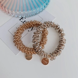 Close-up of amber crystal beaded spiral hair ties with gold handmade metal tags