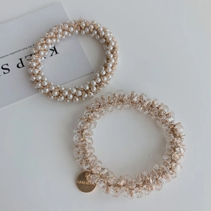 Close-up of handmade pearl and crystal bead hair ties with gold accents and metal tag