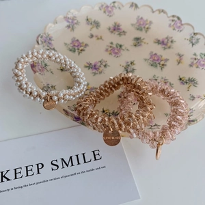 Detailed close-up of pearl and crystal bead elastic hair ties in a ceramic tray
