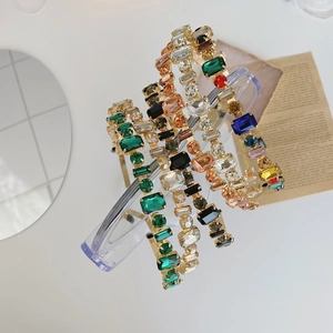 Detailed view of four vintage crystal headbands on a gold metal base in emerald and champagne