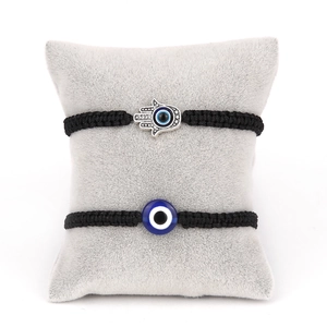 Detailed view of Hamsa Hand and Evil Eye charms on adjustable black braided bracelets