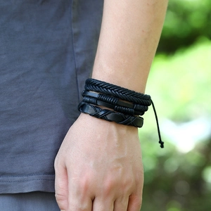 Close-up of four-piece black woven leather bracelet set worn on a model's wrist