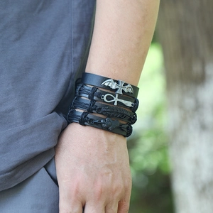 Close-up of a men's layered black leather bracelet set with silver winged cross charms
