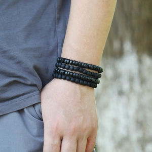 Detailed close-up of four-piece black beaded bracelets with matte and flat stone beads