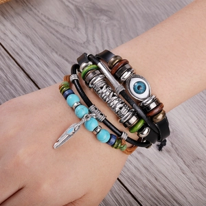 Detail view of multi-layer leather bracelet with evil eye, turquoise, and silver feather charms
