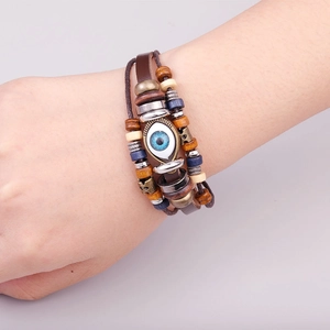 Macro detail of multilayer leather bracelet with evil eye charm and ethnic wood beads