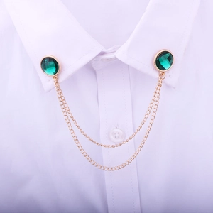 Close-up of green gemstone collar pin with golden double chains on white shirt
