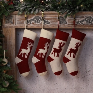Set of four knitted Christmas stockings with reindeer patterns on a wooden mantel