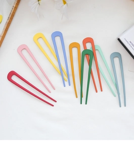 Flat lay of colorful U-shaped metal hairpins with matte finish on white desk