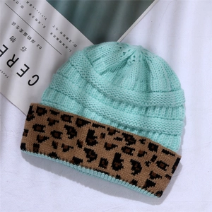 Detail of mint green knitted beanie featuring a leopard print cuff and soft ribbed texture
