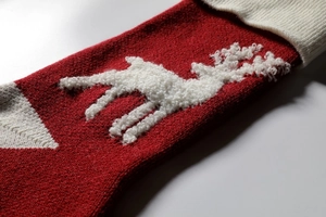 Macro shot of knitted Christmas stocking featuring a 3D plush reindeer and soft texture