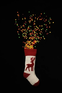 Close-up of white knitted Christmas stocking with red reindeer embroidery and colorful candies