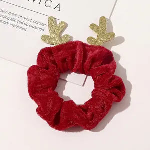 Detail of a Christmas deer antler hair scrunchie in red velvet with gold glitter accents